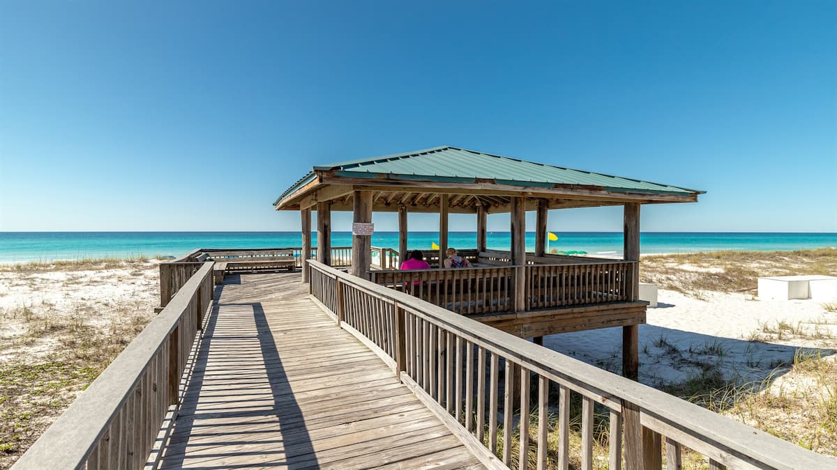 Wooden beachfront gazebo beside white sand and Gulf water
